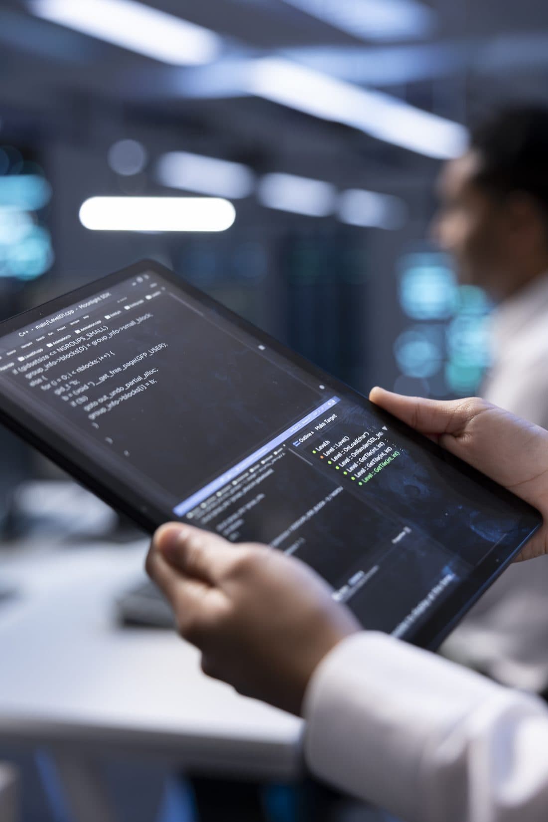 Analista revisando código do Protheus em tablet no datacenter